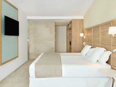 Moderne hotelkamer met twee bedden, houten panelen en flatscreen-tv aan de muur.