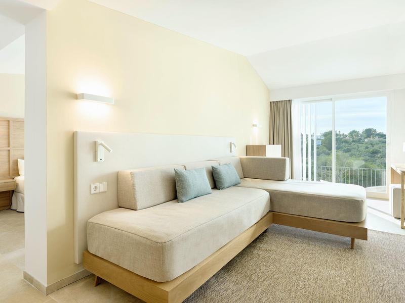 Lichte hotelkamer met twee enkelbedden, beige inrichting en een groot raam met uitzicht.