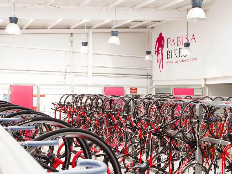 Gran alquiler de bicicletas con muchas bicicletas en un almacén luminoso llamado Pabisa Bike.