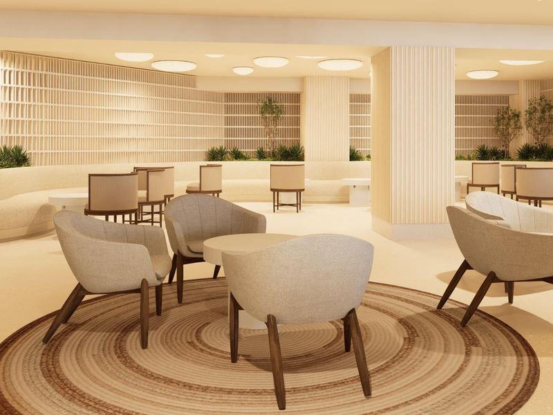 Área de salón moderna y luminosa con sillas cómodas y alfombra redonda en un hotel.