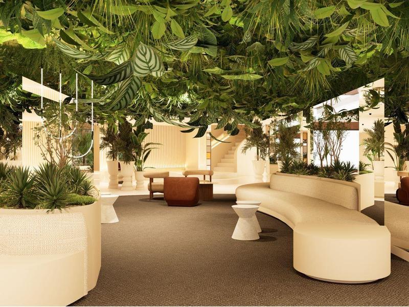 Lobby de hotel luminosa con áreas de asiento curvas y plantas colgantes verdes en el techo.