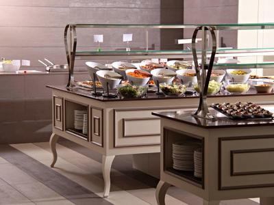 Buffet mit verschiedenen Speisen und Gläsern auf eleganten, hellbraunen Buffetschränken.