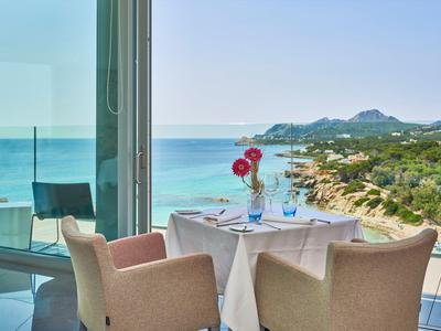 Balkontisch mit zwei Stühlen, Meerblick und blauer Himmel bei Sonnenlicht.