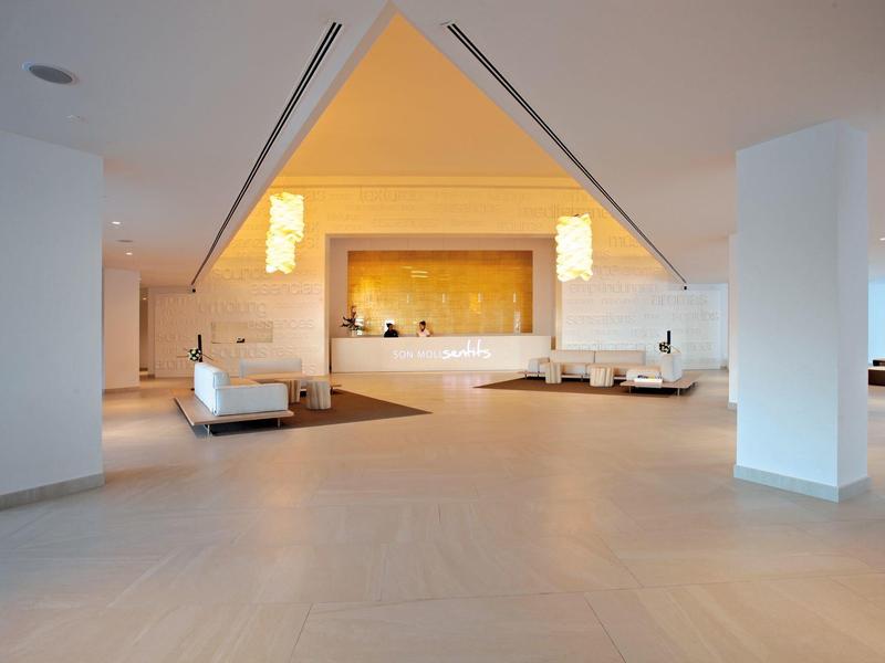 Großer, heller Lobbybereich mit weißem Mobiliar, warmen Beleuchtung und modernem Design.