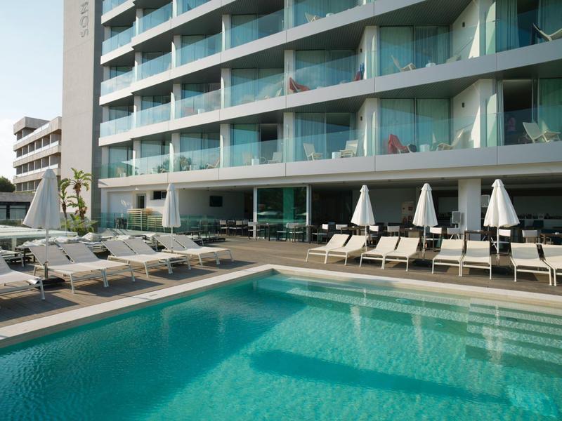 Moderner Hotelpool mit Liegestühlen und Sonnenschirmen vor einem mehrstöckigen Glasgebäude.