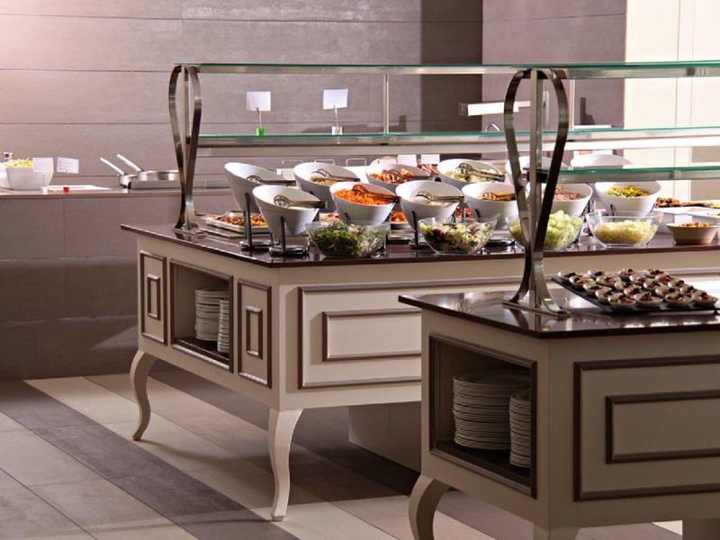 Buffet mit verschiedenen Speisen und Gläsern auf eleganten, hellbraunen Buffetschränken.