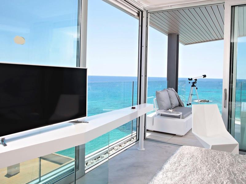 Modernes Wohnzimmer mit Panoramafenstern, Meerblick, weißem Sofa und flachem Fernseher.