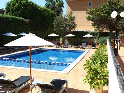 Una piscina rettangolare con acqua blu, circondata da ombrelloni e lettini.