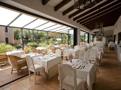 Elegantes Restaurant mit gedeckten Tischen und Blick auf eine Terrasse mit Garten.