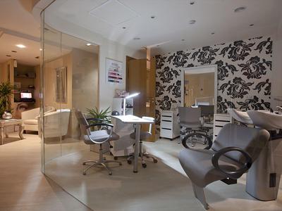 Moderne Friseureinrichtung in einem Hotel mit bequemen Stühlen und stilvoller Tapete.