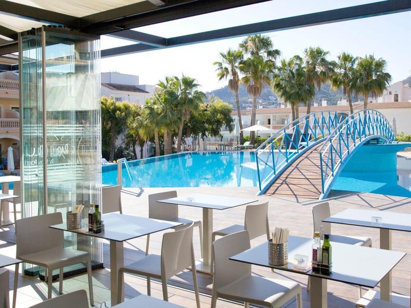 Moderner Außenbereich mit Sitzplätzen am Pool und blauem Bogenbrücke bei Sonnenschein.