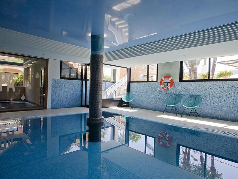 Hallenbad mit blauen Fliesen, zwei Stühlen und großen Fenstern für Tageslicht.