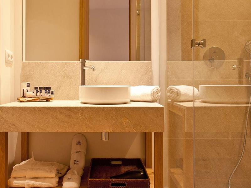 Modernes Badezimmer mit Waschbecken auf Holzplatte, Spiegel, Handtüchern und durchsichtigem Duschbereich.