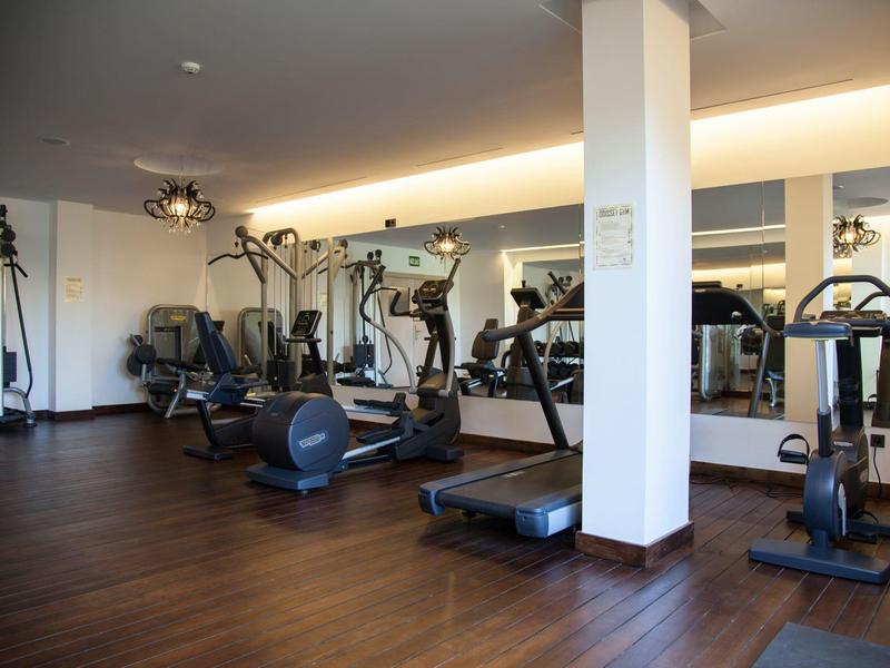 Gimnasio moderno con varios equipos de entrenamiento y suelo de madera en un hotel.