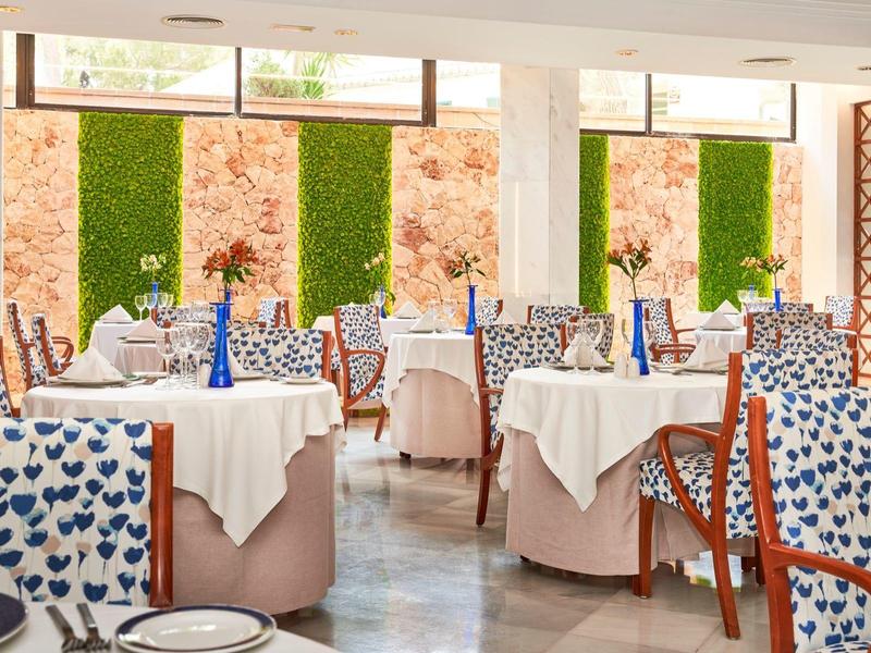 Restaurante luminoso con mesas elegantemente preparadas y sillas estampadas para los huéspedes.