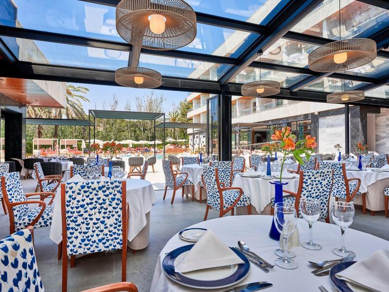 Restaurante elegante con techo de cristal y sillas azul-blancas, luminoso y acogedor.