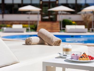 Two rolled towels and breakfast with waffles by a hotel pool.