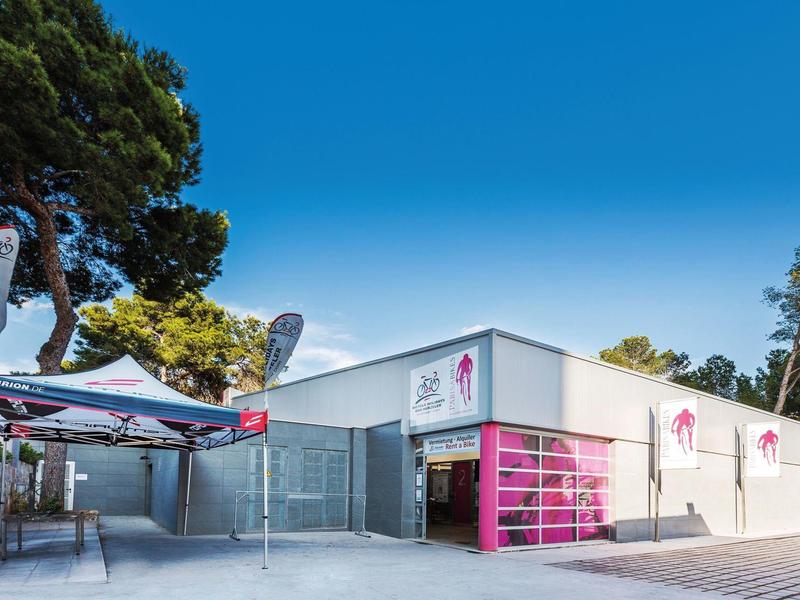 Modern white building with pink accents and clear sky in a peaceful setting.