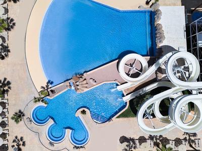Luftaufnahme eines großen Wasserparks mit mehreren Schwimmbecken und verschlungenen Wasserrutschen.