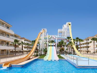 Wasserpark mit bunten Rutschen, großem Pool, Palmen und mehreren mehrstöckigen Gebäuden.