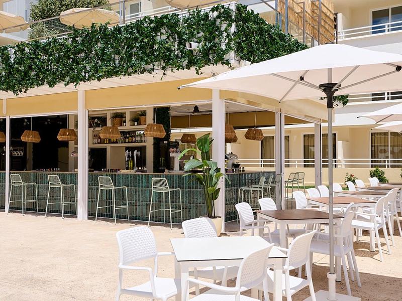 Terrazza dell'hotel con sedie bianche e ombrelloni sotto il sole.