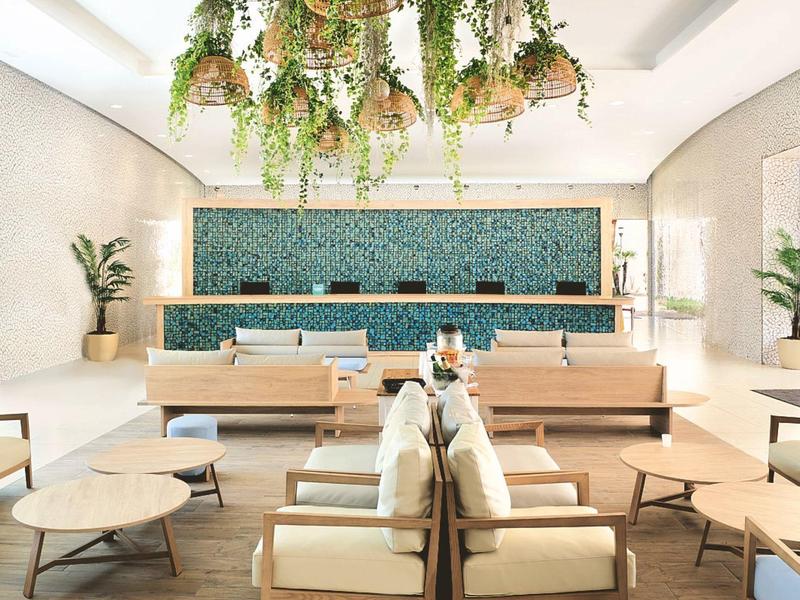 Sala d'attesa moderna con divani, tavolini e piante sospese.