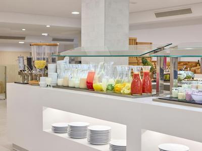 Saftbar in heller Cafeteria mit Karaffen, Gläsern und weißem Geschirr sauber arrangiert.