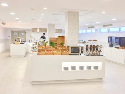 Helle, moderne Kantine mit weißen Wänden, gedeckten Tischen und Selbstbedienungsbuffet.