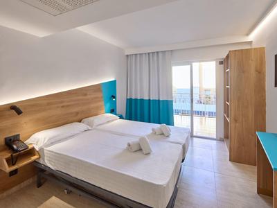 Modernes Hotelzimmer mit zwei Einzelbetten, Holzmöbeln und Balkon mit Meerblick.