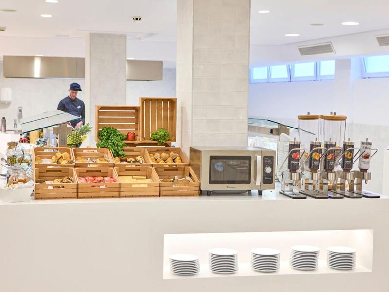 Buffet mit frischem Obst, Müslispendern und Mikrowelle in modernem, hellen Raum.