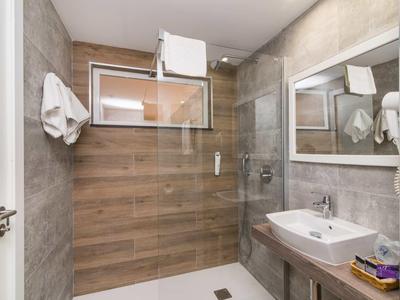Modern bathroom with walk-in shower, large mirror, and towels hanging on the wall.