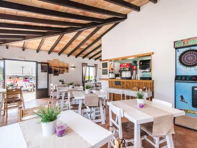 Bright restaurant with wooden beam ceiling, white tables and chairs, plants, and arcade machines.