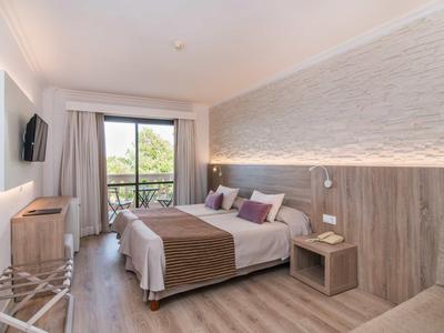 Modern hotel room with double bed, wood flooring, balcony, and wall-mounted TV.