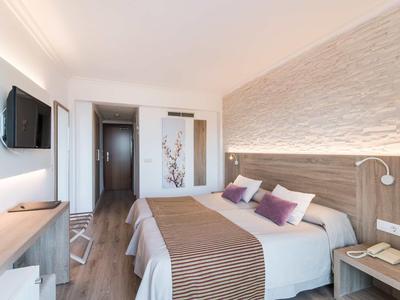 Modern hotel room with double bed, TV, desk, and cozy lighting.