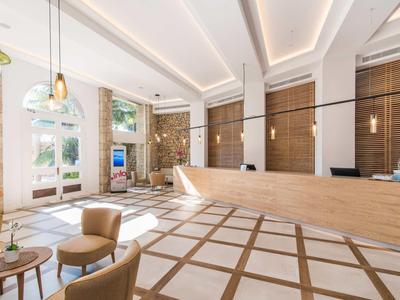 Modern hotel lobby with light stone, wooden accents, and comfortable seating.