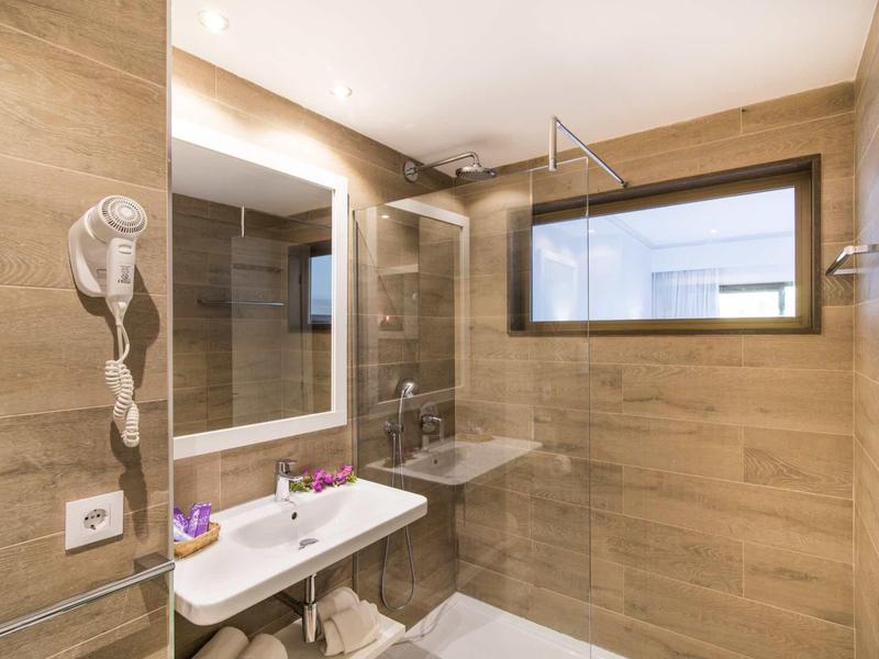 Modern bathroom with brown wall tiles, large mirror, and shower with glass partition.
