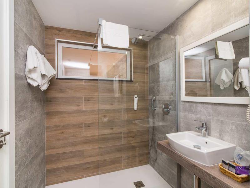 Modern bathroom with walk-in shower, large mirror, and towels hanging on the wall.