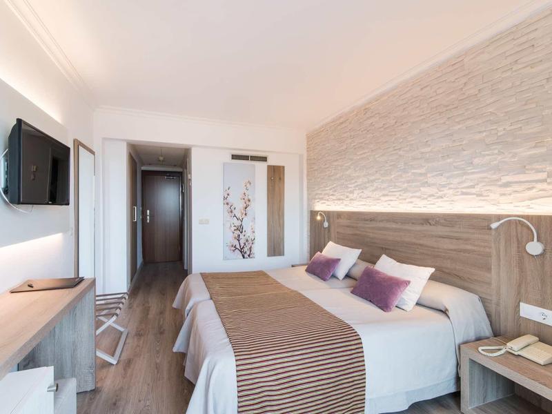 Modern hotel room with double bed, TV, desk, and cozy lighting.