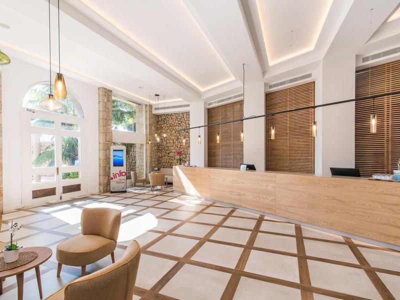 Modern hotel lobby with light stone, wooden accents, and comfortable seating.