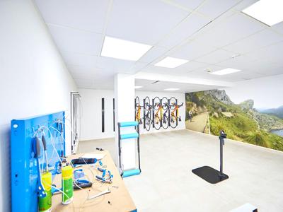 Stanza luminosa e moderna con stazione di riparazione biciclette e murale panoramico di paesaggio montano