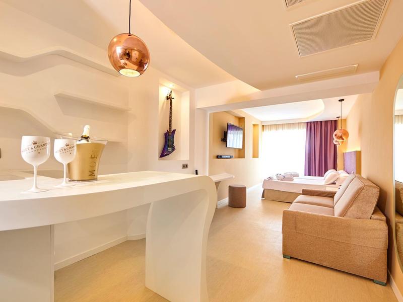 Modern hotelkamer met zithoek, tv en toegang tot balkon.