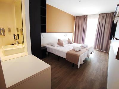 Camera d'hotel moderna con due letti singoli, scrivania e bagno con doccia.