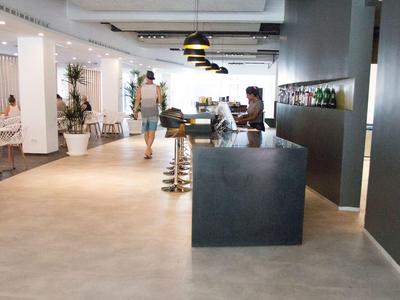 Lobby di un hotel moderna e luminosa con reception, aree salotto e arredamento elegante.