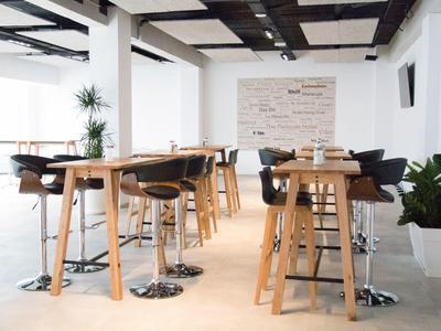 Area pranzo moderna con tavoli alti in legno e sedie nere in una stanza luminosa