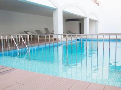 Piscina coperta con ringhiera metallica e sedie a sdraio in uno spazio luminoso e moderno