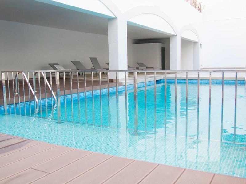 Piscina coperta con ringhiera metallica e sedie a sdraio in uno spazio luminoso e moderno