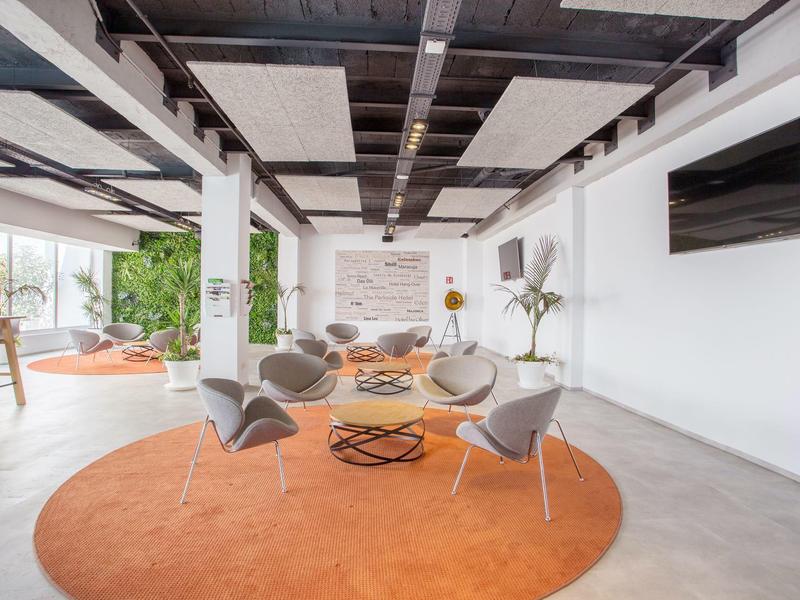 Lounge luminosa con sedie moderne attorno a un tappeto rotondo e ampie finestre