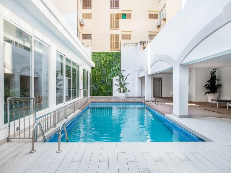 Cortile moderno con piscina rettangolare e pavimento bianco in un hotel.