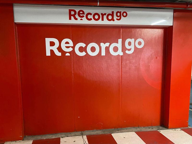 Cartello pubblicitario rosso acceso per Record go contro un muro rosso.