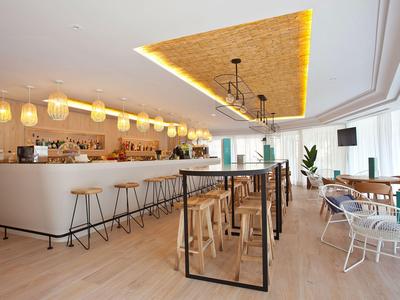 Area bar dell'hotel moderna con sgabelli in legno, bancone e illuminazione elegante.